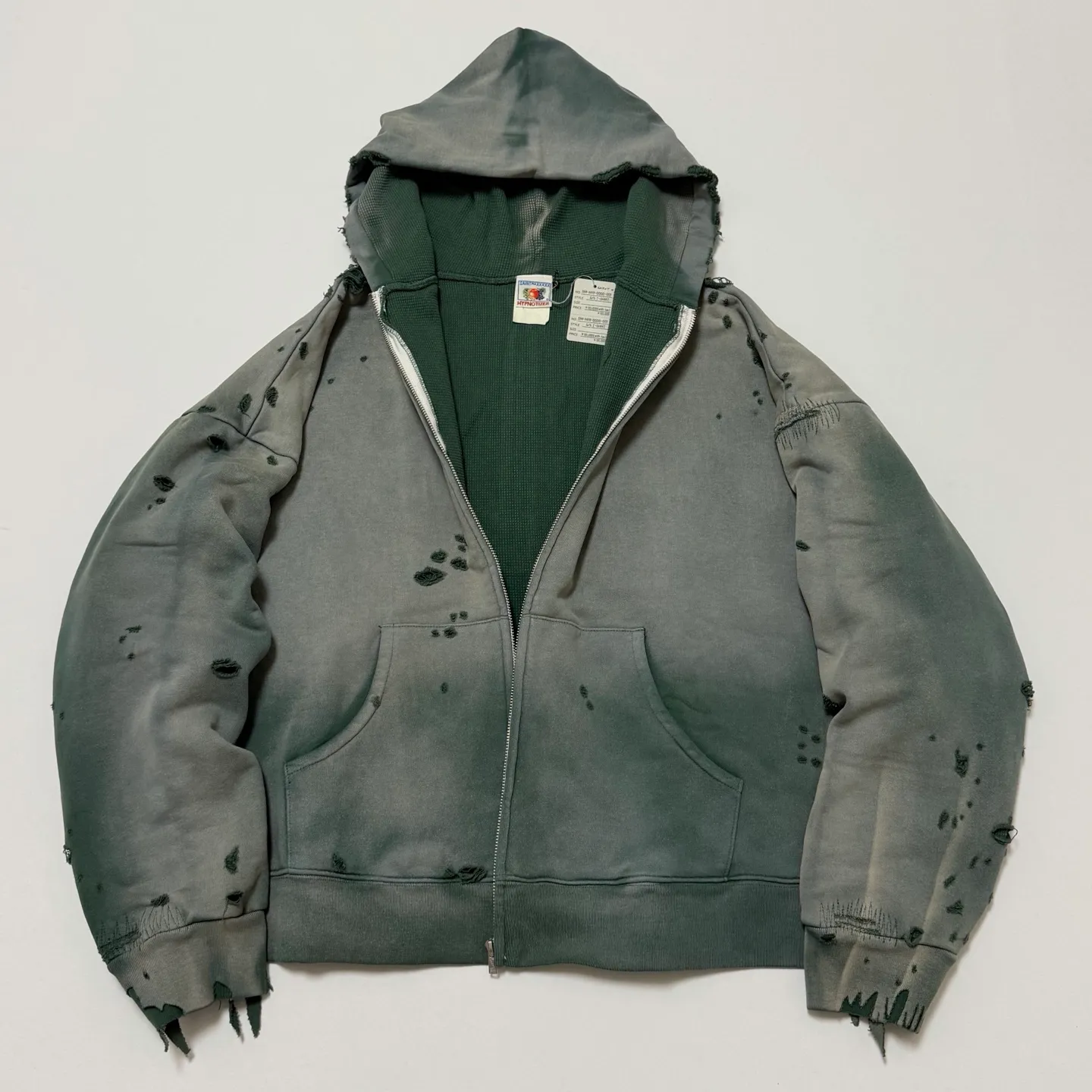 More details SAINT Mxxxxxx DBL FACE ZIP UP HOODIE/GREEN Double-layer damaged waffle zipper jacket, washed green S-XL, a style that has been used in the summer. After continuous fine polishing, it is finally shipped. The finished product is simply a work of art. Super heavy washing and distressing. Multiple horse water fading. Many hand-made wormhole damage processing. Deconstruction and reorganization embroidery technology. Customized zipper with LOGO. The color details of the zipper webbing are also correct. Original grade fruit main label and wash water label. Top purchasing grade. A layer of waffle fabric is added to the inner lining to make the overall texture stronger and increase the comfort and warmth of the wearer.